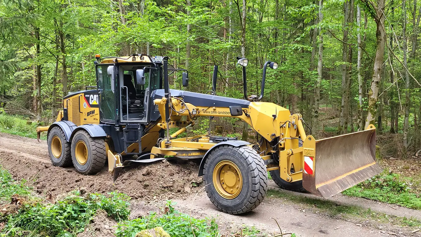 Grader profiliert Waldweg beim Wegebau